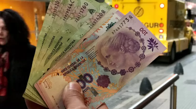 Un hombre muestra pesos argentinos frente a un banco en el distrito financiero d