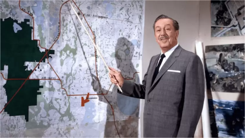 Walt Disney con un mapa de los terrenos donde construyó los parques