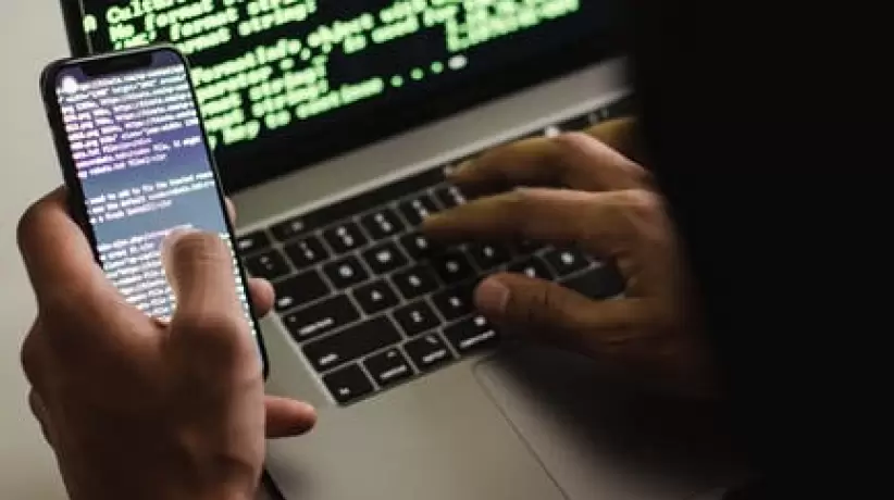 Hacker Irreconocible Con Smartphone Escribiendo En La Computadora Portátil En El