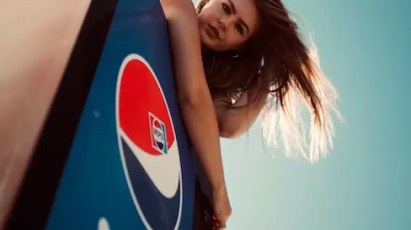 Foto De ángulo Bajo De Mujer En La Parte Superior De La Nevera Pepsi Posando