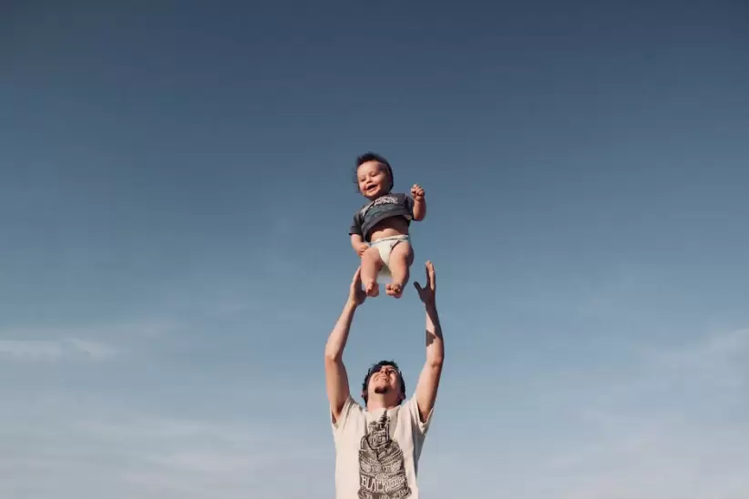 Foto De Un Hombre Criando A Un Bebé Bajo Un Cielo Azul, padre
