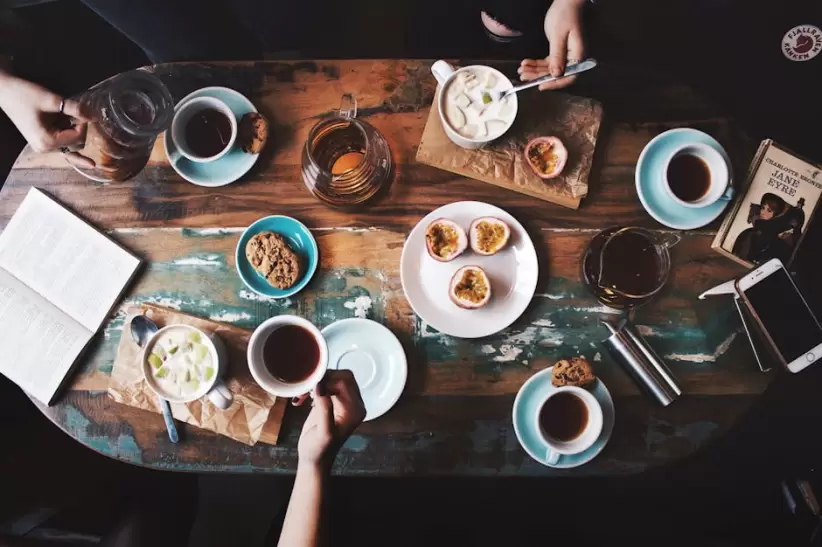 Persona Sentada Junto A La Mesa Con Tazas De T Y Platos