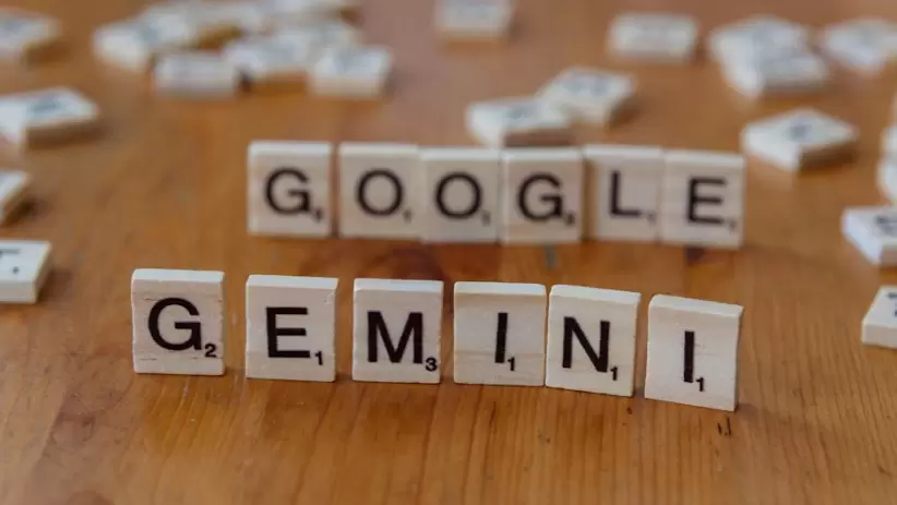 Fichas de Scrabble que forman las letras Google y Gemini sobre una mesa de madera, centrndose en conceptos de IA.