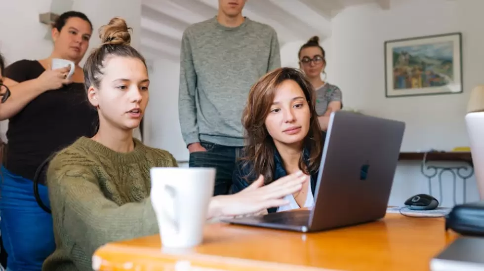 Mujer En La Parte Superior Verde Con Macbook Junto A Un Grupo De Personas