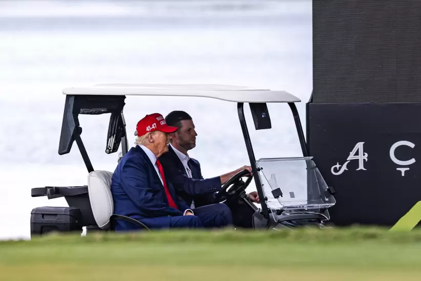DORAL, FLORIDA - APRIL 03: U.S. President Donald Trump and his son Eric Trump drive in a golf cart after arriving on Marine One on the ninth hole duri