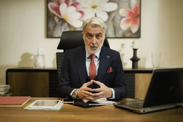 Hombre de negocios profesional de mediana edad sentado con confianza en su escritorio ejecutivo en un entorno de oficina. (Foto: Pexels)