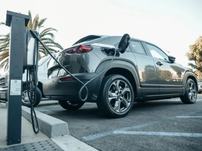 Vehículo eléctrico moderno cargando en una estación exterior durante el día. (Foto: Pexels)