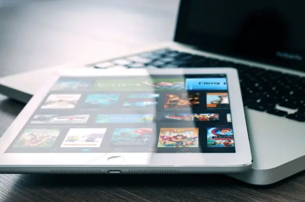 Tableta que muestra servicios de streaming en un portátil, ilustrando la configuración de entretenimiento digital.