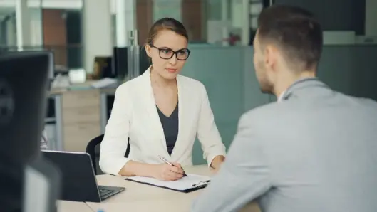 Dos profesionales en una reunión de negocios seria en un entorno de oficina moderna. (Foto: Pexels)