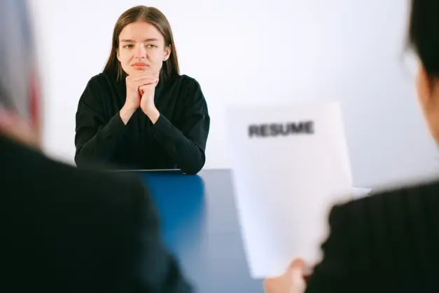 Una mujer en una entrevista de trabajo frente a dos empleadores con enfoque en su currículum. (Foto: Pexels)