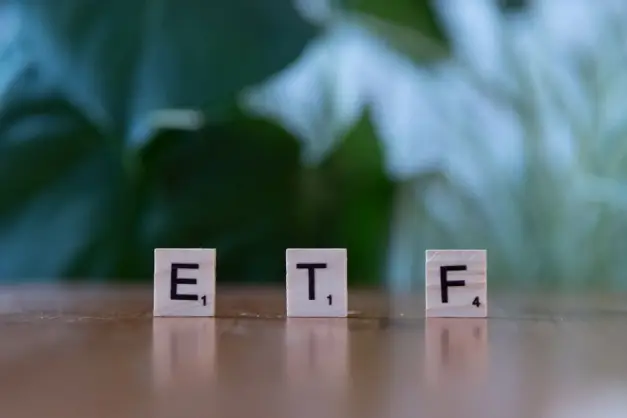 Fichas de Scrabble escribiendo ETF sobre una superficie de madera con fondo verde difuminado. (Foto: Pexels)