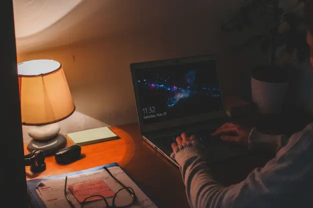 Iluminación ambiental cálida en un espacio de trabajo con un portátil y una lámpara de mesa creando una atmósfera acogedora. (Foto: Pexels)