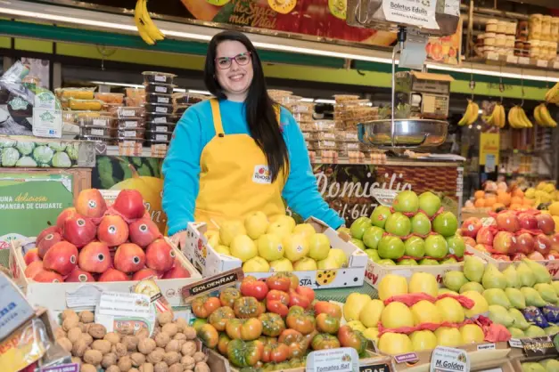 Mujer sonriente en un mercado de frutas en Madrid, rodeada de productos frescos. (Foto: Pexels).