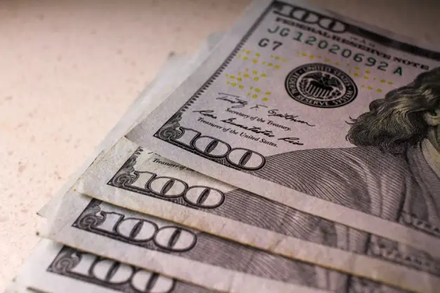 Vista de cerca de múltiples billetes de 100 dólares apilados sobre una superficie clara y texturizada. (Foto: Pexels)