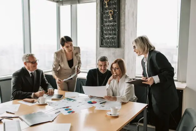 Profesionales de negocios participan en una reunión de oficina para analizar datos y estrategias.