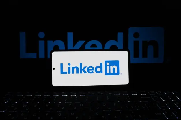 Teléfono inteligente que muestra el logotipo de LinkedIn con teclado y un logotipo de fondo grande, tema empresarial. (Foto: Pexels)