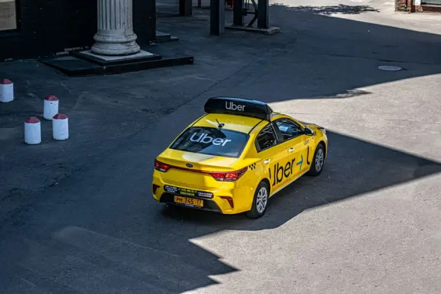 Un taxi Uber amarillo circulando por una calle de la ciudad, mostrado desde arriba. (Foto: Pexels)