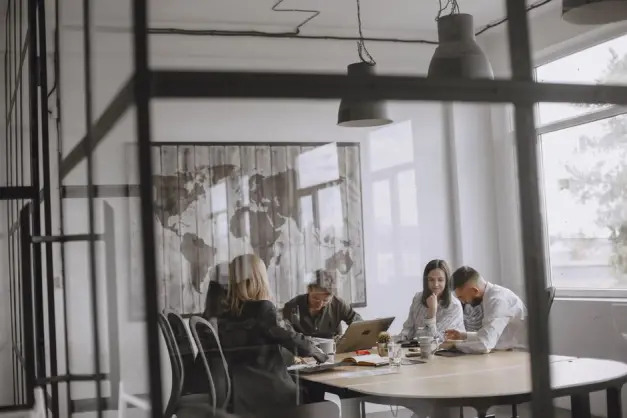 Un grupo de profesionales colabora en una oficina moderna con una decoración de mapa mundial. (Foto: Pexels)