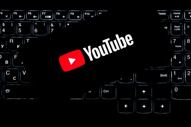 Logotipo de YouTube mostrado en un teclado retroiluminado, que representa los medios digitales y la creación de contenido en línea.