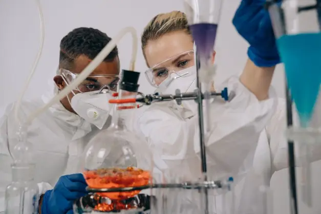 Dos científicos con equipo de protección realizando experimentos de química en un laboratorio. (Foto: Pexels)