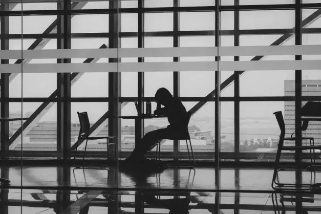 Una silueta de una persona trabajando en un interior moderno con grandes ventanas y mesas. (Foto: Pexels)