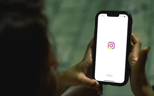 Primer plano de una mujer sosteniendo un smartphone que muestra la aplicación de Instagram en interiores. (Foto: Pexels)