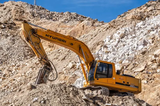Excavadora Hyundai amarilla operando en una cantera rocosa bajo un cielo azul claro. Perfecto para temas industriales. (Foto: Pexels)