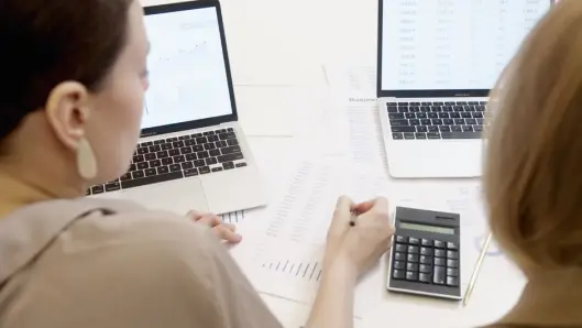 Dos personas analizando datos empresariales en laptops con gráficos y tablas. (Foto: Pexels)