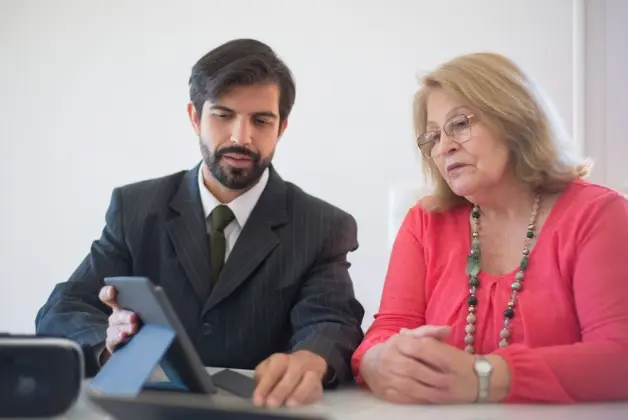 Reunión de negocios en Portugal entre un hombre y una mujer mayor discutiendo con una tablet. (Foto: Pexels)