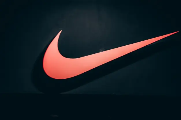 Logotipo vibrante del swoosh rojo de Nike exhibido sobre un fondo oscuro y minimalista que simboliza deportes y estilo de vida. (Foto: Pexels)