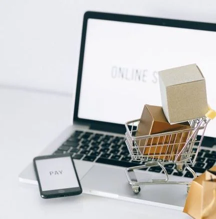 Mini carrito de compras en un portátil simbolizando compras en línea y transacciones de comercio electrónico. - Pexels