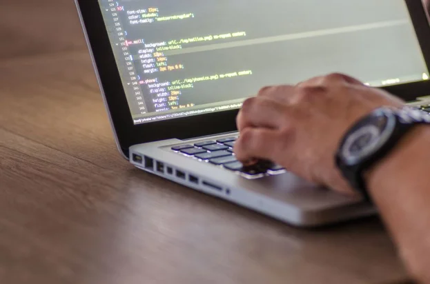 Una toma de cerca de una persona codificando en un laptop, enfocándose en las manos y la pantalla.