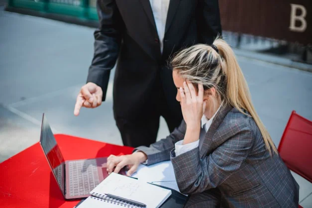 Profesionales de negocios discutiendo trabajo en una laptop en una mesa roja al aire libre.