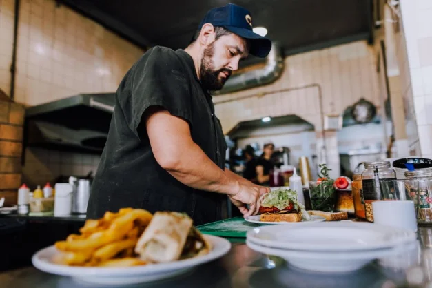El chef prepara hábilmente un sándwich en un vibrante ambiente de cocina en Buenos Aires.