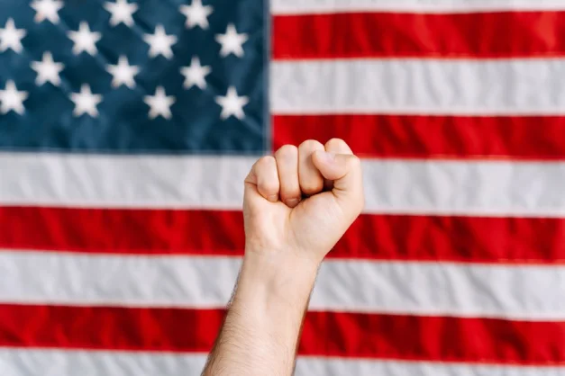 Un puño levantado frente a una bandera americana, simbolizando patriotismo y activismo.