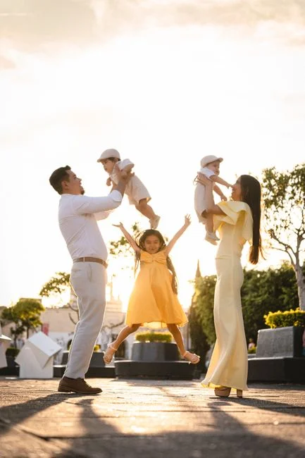 Familia feliz de cuatro disfrutando de un momento juguetón en un parque iluminado por el sol.