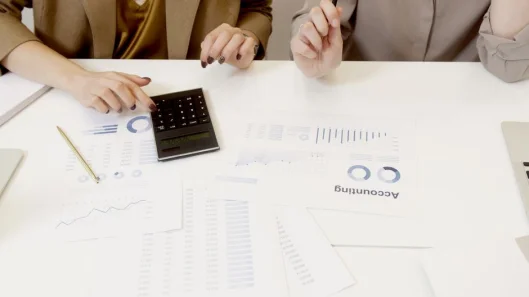 Dos profesionales analizando documentos financieros con una calculadora.