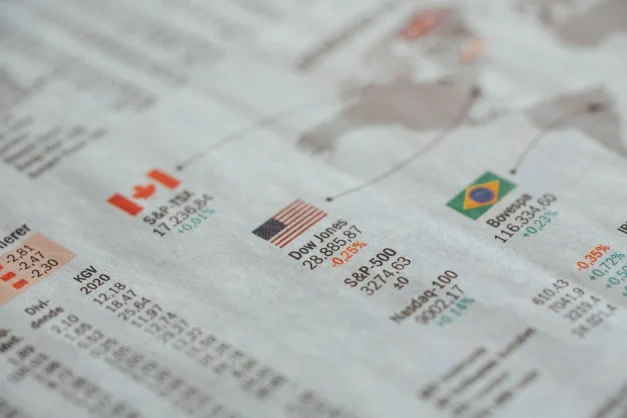 Primer plano detallado de un periódico que muestra estadísticas del mercado financiero global y banderas de países.