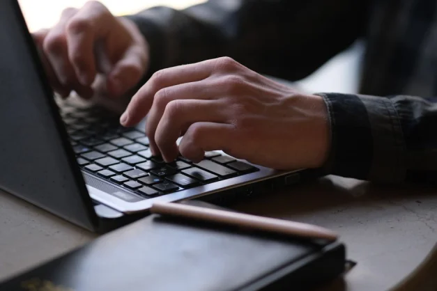 Foto en primer plano de manos escribiendo en un portátil, perfecta para temas de trabajo remoto o nómadas digitales.