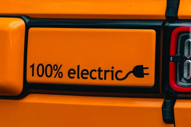 Vehículo eléctrico de color naranja brillante con el emblema "100% eléctrico", que pone de manifiesto la importancia del transporte ecológico.