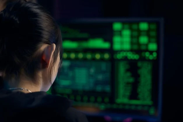 Una mujer se concentra en los datos mostrados en una pantalla de ordenador en una habitación oscura.