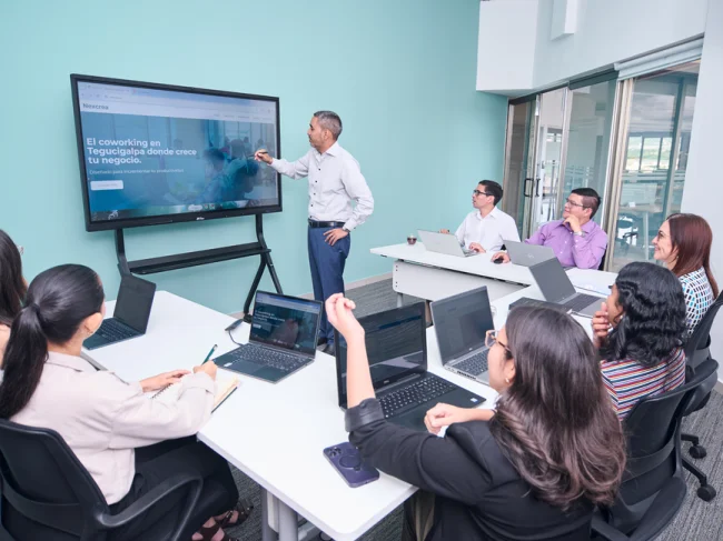 Equipo profesional realizando una presentación de negocios con computadoras portátiles y una pantalla de proyector.