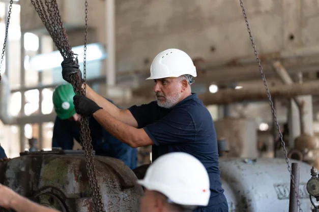 Trabajadores con cascos operando cadenas en un entorno industrial, Libia.