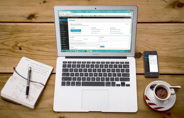 Una acogedora escena de oficina en casa con un portátil, bloc de notas, smartphone y café, perfecto para la productividad.