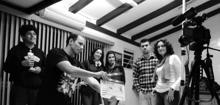 Un grupo de adultos colabora en un proyecto de filmmaking, visto sosteniendo un clapperboard en interiores.